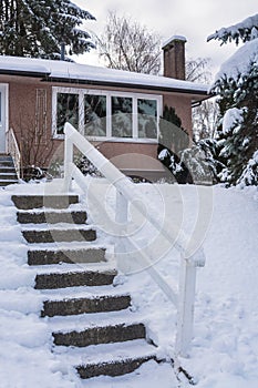 Stair way to the entrance of family house over front yard in snow