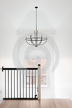 A staircase with a chandelier hanging from a tall ceiling.