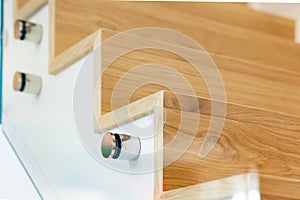 Staircase covered in oak parquet with tempered glass balustrade and chromed pins