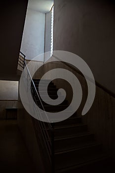 Staircase lit by a feeble light coming from a window