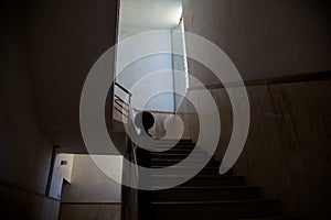 Staircase lit by a feeble light coming from a window