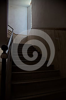 Staircase lit by a feeble light coming from a window