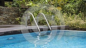 A staircase with a metal railing descends into the swimming pool.