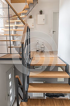 Staircase of a private house with modern stairs. Steel frame with wooden steps, white and gray walls, harmonious color concept.