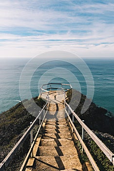 Stairs above the ocean with a blue sky on the background