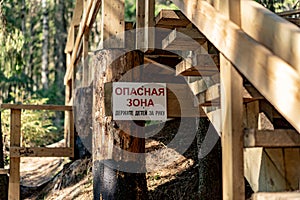 stairs of bridge over mountain river in wildlife area with a plate in russian Dangerous zone. Hold children by hand.