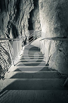 Stairs going down to cave with river flowing in underground cavities, rock formation