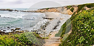 Stairs going down to a sandy beach on the Pacific Ocean coastline, Pescadero State Beach, California