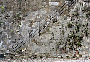 Stairs and iron railing along a stone wall