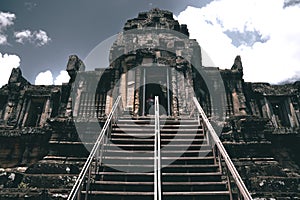 Stairs leading to an ancient temple at Angkor Wat temple complex against a cloudy sky