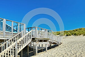 Stairs leading up to small wooden beach pavilion restaurant called `Paal 19` on a summer day on island Texel in Netherlands