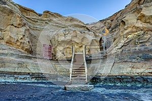 Stairs provide a path for hikers to ascend from the beach up the brown cliffs.