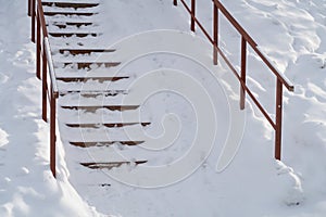 Stairs steps with metal railing covered with snow, winter background