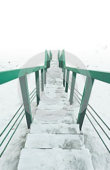Stairs to nowhere concept. green railings and steps in snow. View to white space
