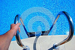 Stairs to the pool filled with clean water. Hand holds the handrail