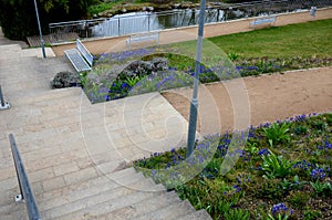 Between the stairs is a waterfall with stones and boulders. artificial stream with a waterfall between the stairs. lawns and flowe