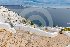 Stairs and white houses. View over caldera with blue sea bay from Oia village of Santorini island in Greece