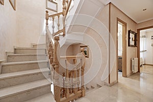 Stairs with wooden railing in a multi-storey detached house with cream-coloured polished marble floors and steps