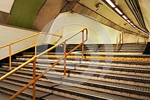 Stairs and yellow rail leading to underground train tunnel