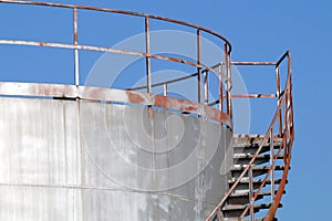 Stairway casts a heavy on an old silver storage tank. Stairs