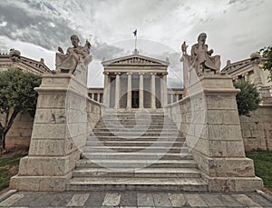 Stairway between Plato and Socrates statues in front of the national academy of Athens, Greece under an impressive cloudy sky