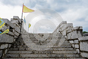 Stairway of stone wall with parapets and flags in cloudy afternoon