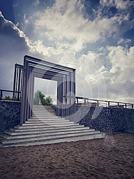 Stairway to heaven concept. Door to the sea on bright morning light on the sky. Outer staircase with wooden gate and fence.