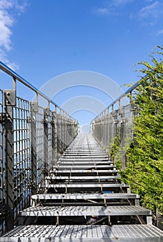 Stairway to heaven - steel staircase going up to a blue sky with clouds