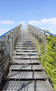 Stairway to heaven - steel staircase going up to a blue sky with clouds