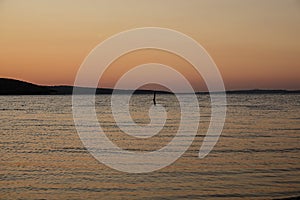 a stake in the ocean at sunset