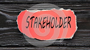 STAKEHOLDER - word on a red torn piece of paper on a dark wooden background