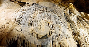 Stalactite and stalagmite formations on the rocky walls of a large underground cave