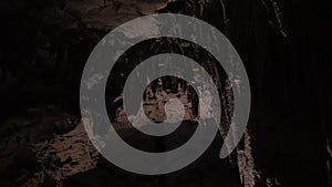 Stalactites in a stone cave, wind blowing dry grass, dark cave