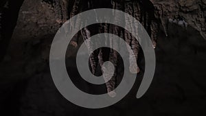 Stalactites in a stone cave, wind blowing dry grass, dark cave