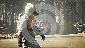 A Stalker in a chemical protection suit and a gas mask walks through a summer Sunny forest. The concept of a post