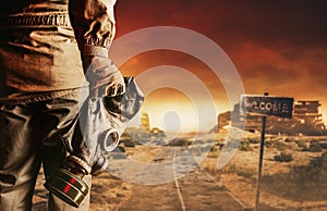 Stalker holding gas mask on wasteland background photo