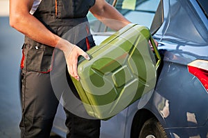 Stalled car filling with gasoline by professional worker.