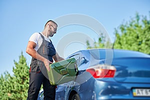 Stalled car filling with gasoline by professional worker.