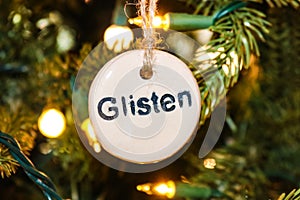 Stamped Glisten Christmas ornament on tree with strings of lights