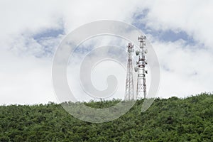 Stanchion of Telecommunication mast TV antennas wireless technology on a hilltop of green mountain, blue sky and cloud