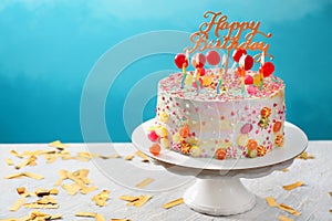 Stand with beautiful tasty birthday cake on table against color background