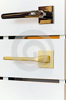 A stand of doorknobs in a store. Metal door handles of golden and bronze color photo