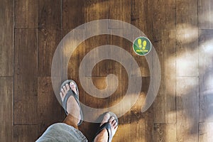 STAND HERE foot sign or symbol on the wooden floor in coffee shop. Coffee shop set foot sign for social distancing to order coffee