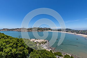 Stand high and watch the sea scenery under the blue sky, blue water, white waves and black rocks