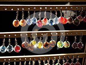 A stand with multi-colored home-made earrings hanging on it