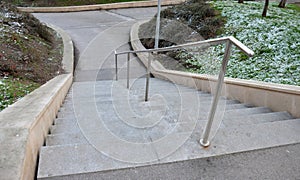 Stand in the park made of concrete with a handle made of shiny, stainless steel metal pipes. lower railing is a protection against