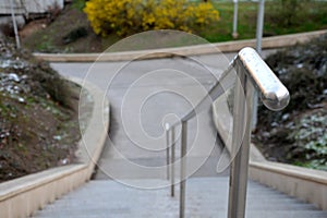 Stand in the park made of concrete with a handle made of shiny, stainless steel metal pipes. lower railing is a protection against