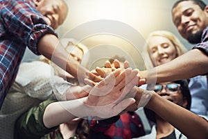 We stand united. a group of people putting their hands together.