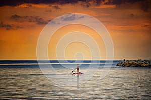 Stand Up Paddle Board Woman Silhouette on Water, Cagliari, Italy. Natural background with Mediterranean sea at sunrise, The sun