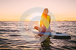 Stand up paddle boarding on a quiet sea with warm summer sunset colors. Relaxing on ocean